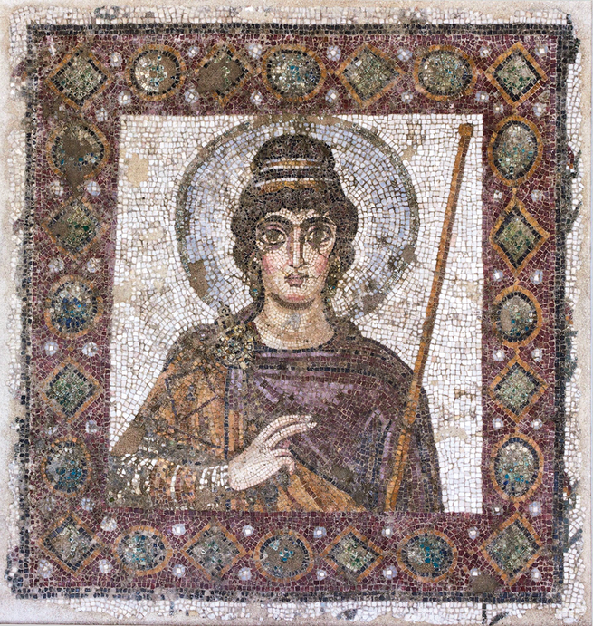 photo of mosaic image of haloed, dark-haired woman with large eyes, right hand raised, surrounded by patterned tile border