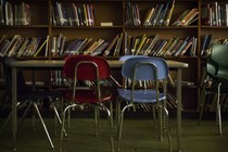 A red chair next to a blue chair in front of a desk and bookshelf