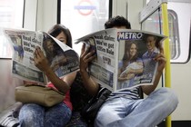 People read newspapers on the London Tube.