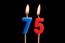 two birthday candles, a blue seven and a red five, are lit with high flames.