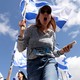 Low angle shot picture of woman holding Israeli flag and screaming.