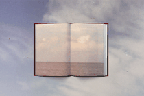 A book opened to an image of an open horizon, set against a blue sky