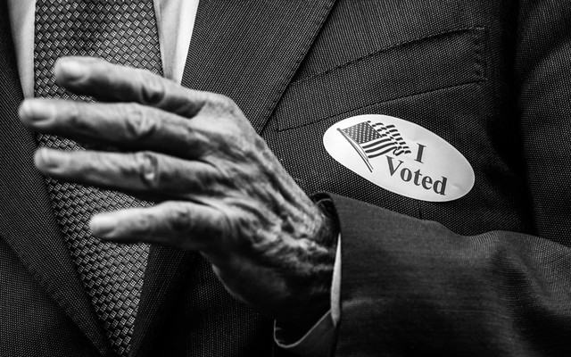 An elderly person wearing an “I voted” sticker