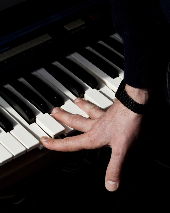 a hand pressing down on the keys of a piano