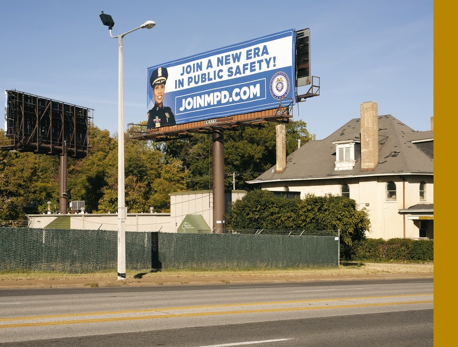 A sign advertising police jobs next down to a rundown house