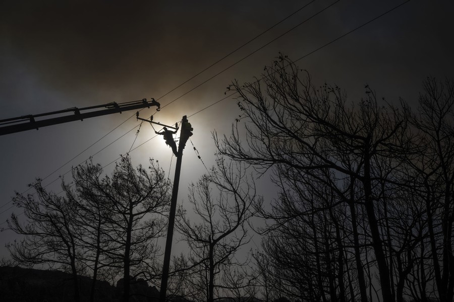 A worker climbing on a utility pole repairs cables.