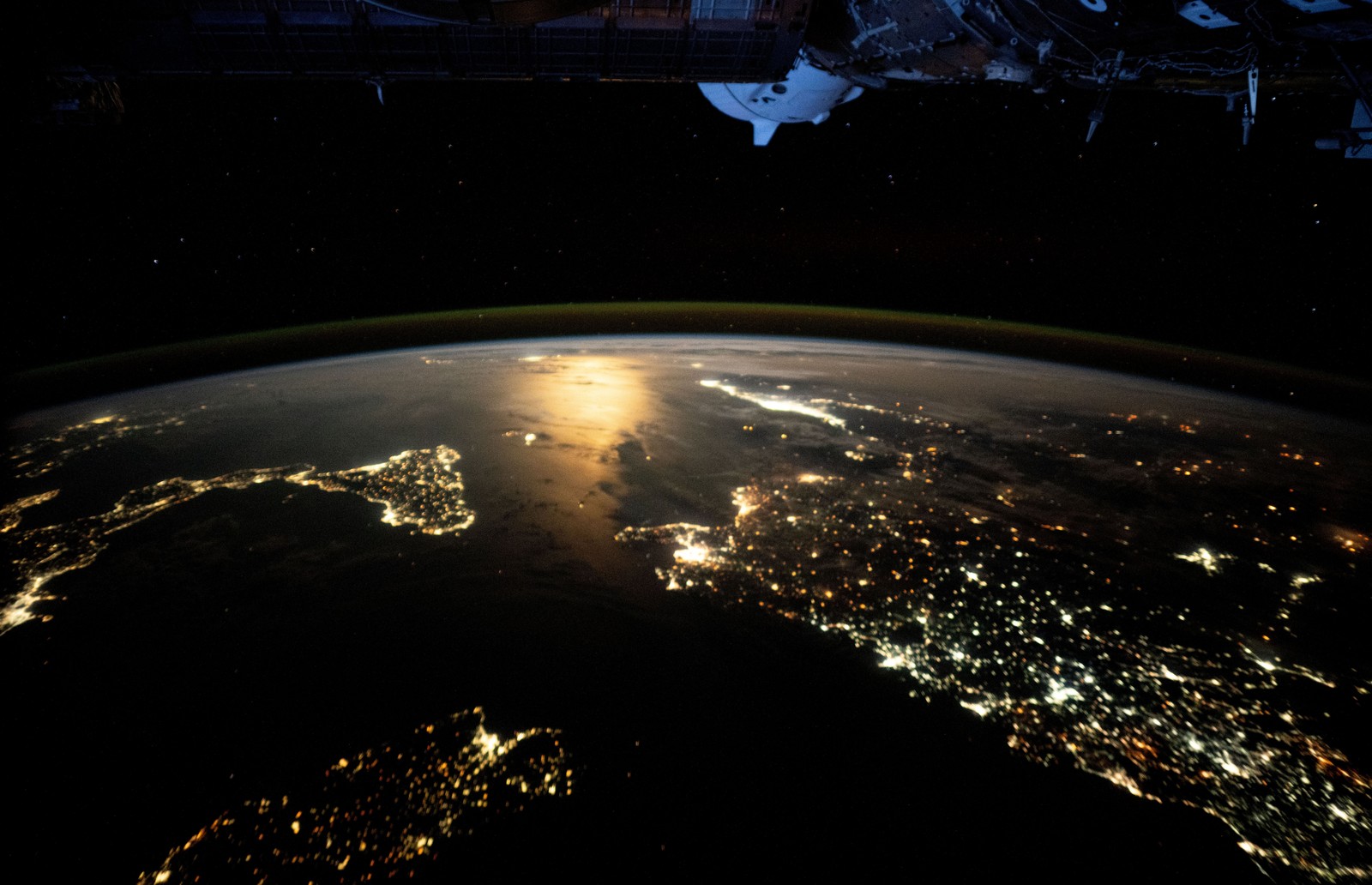 Moonlight is reflected in the Mediterranean Sea, seen among the lights of Italy and other countries.