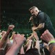 Ken Casey, front man of the Dropkick Murphys holds a microphone up to his mouth while reaching into the crowd at a concert