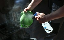 A person sprays a cloth with cleaning solution.