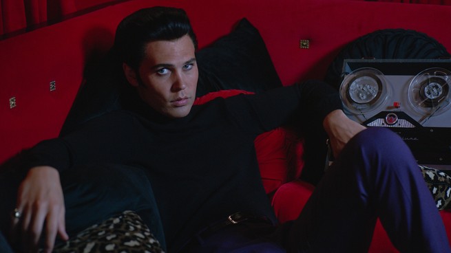 Austin Butler as Elvis Presley, lounging on a red couch in Baz Luhrmann's "Elvis"
