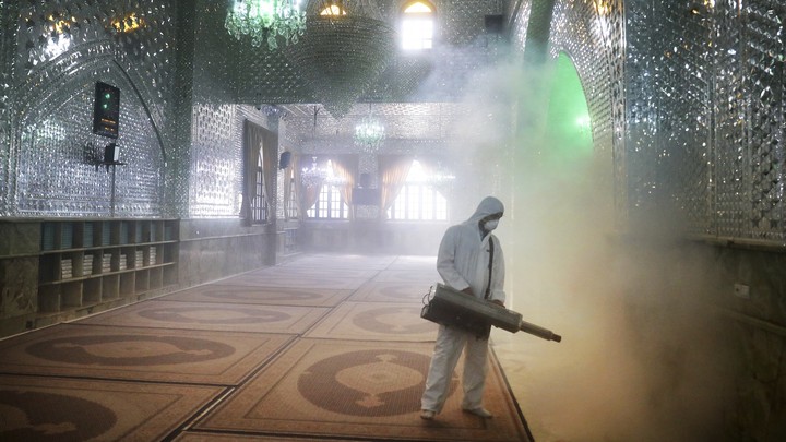 A worker in a protective suit sprays a disinfectant