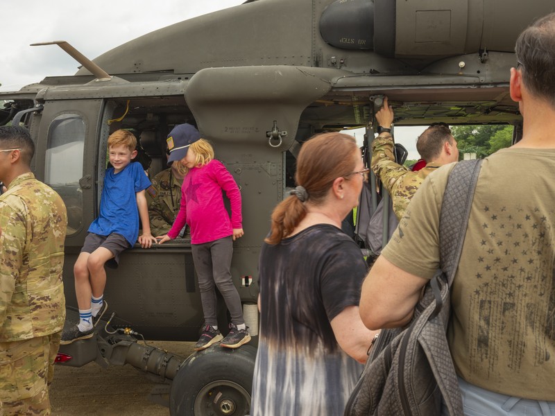 Picture children climbing inside a Black Hawk, part of a display of military equipment parked on the National Mall.
