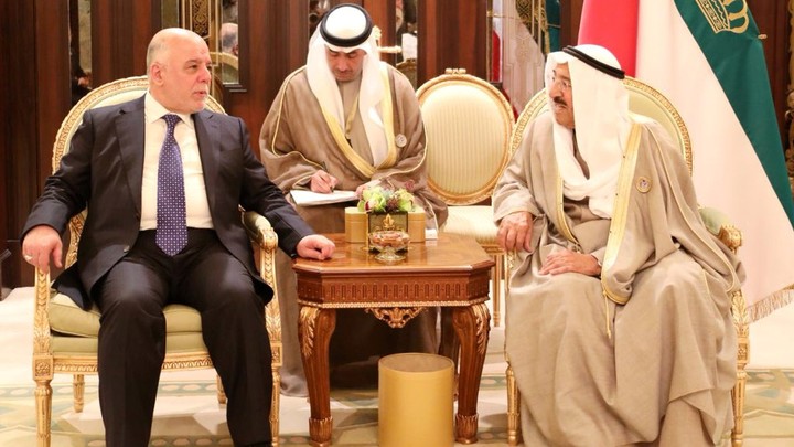 Iraq's prime minister, who is dressed in a suit, talks to the emir of Kuwait, who is dressed in traditional clothes.