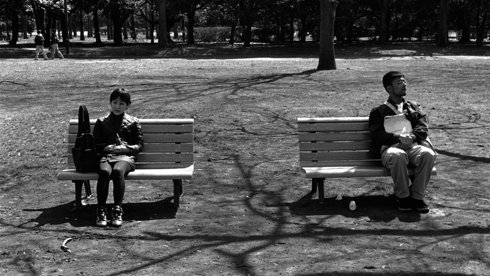 People sitting far apart on benches