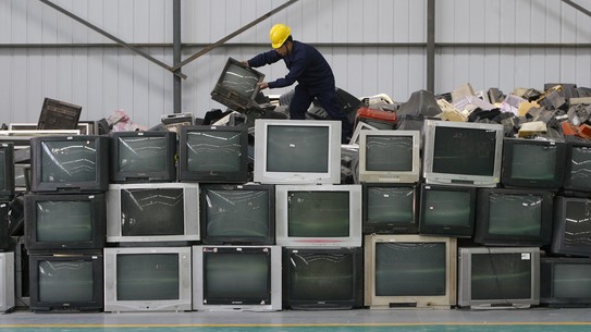 An employee arranges discarded televisions at an electronic waste recycling factory in Wuhan, China, in 2011.