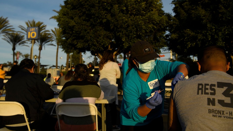 A nurse injects a vaccine dose into someone's shoulder