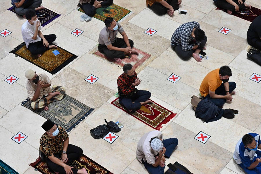Men sit together on prayer mats.