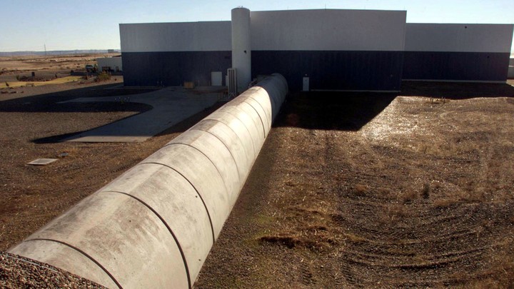Concrete and steel tubes next to a plain building in a brown landscape