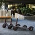 Three Bird electric scooters lined up on a sidewalk
