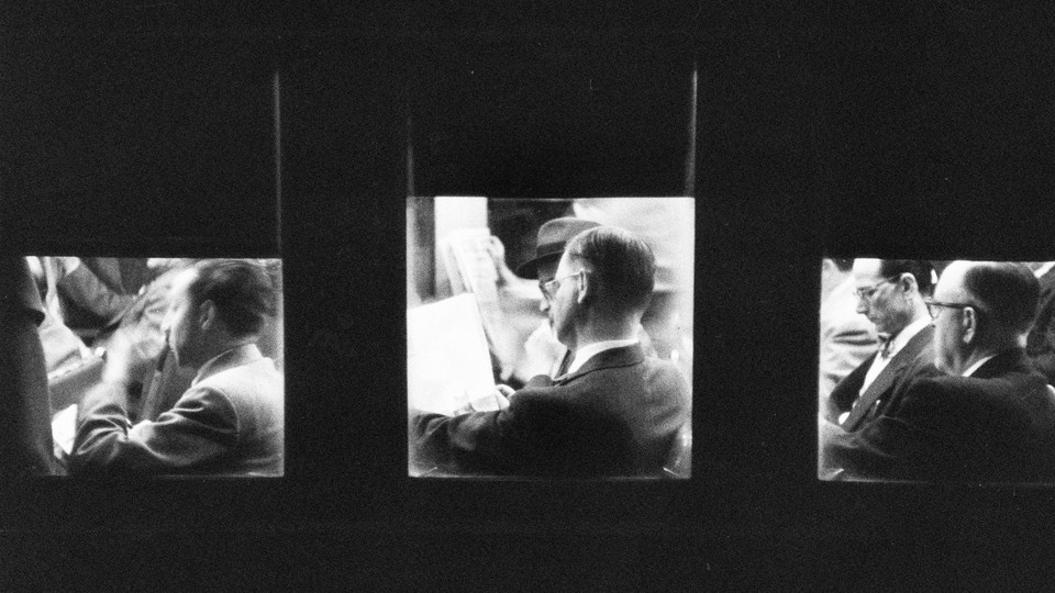 A photograph of three men reading the newspaper, each framed in a window of what looks to be a building with shades partially down on each window