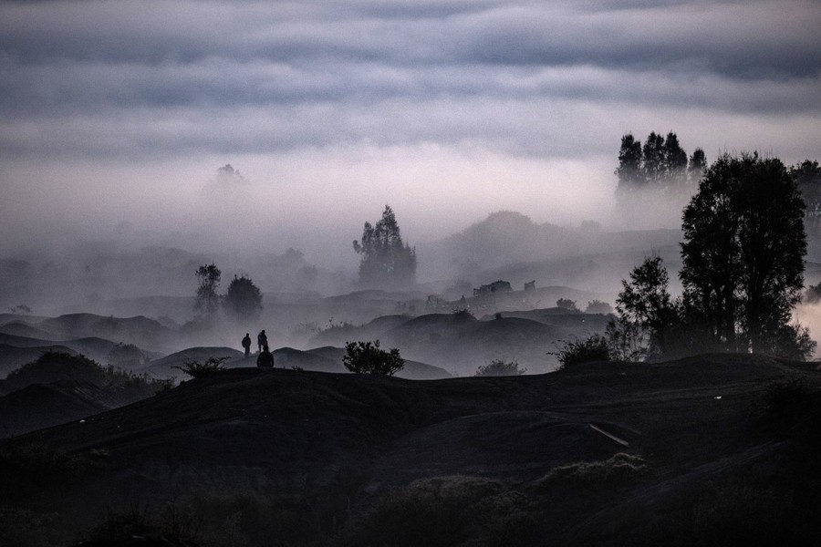 People walk through a foggy valley.
