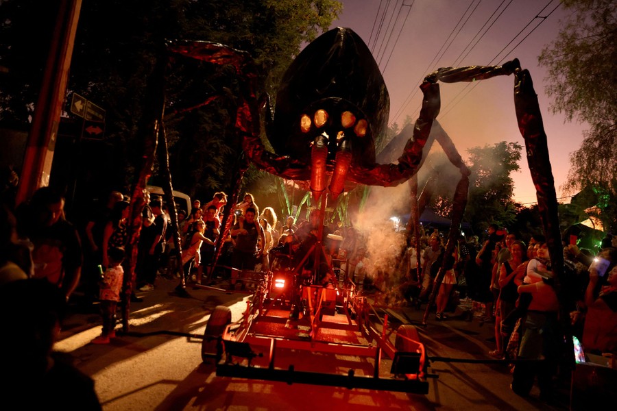 A giant spider puppet is operated in a parade at night.