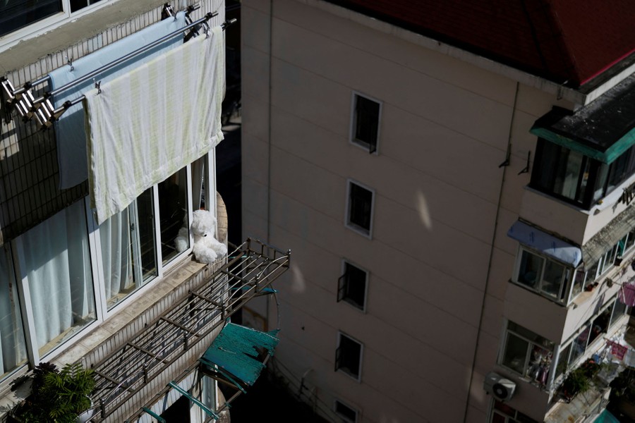 A view of apartment buildings, in which one of them has a stuffed bear sitting in an open window.