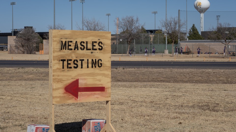 A wooden sign reads "MEASLES TESTING" and has an arrow pointing to the left