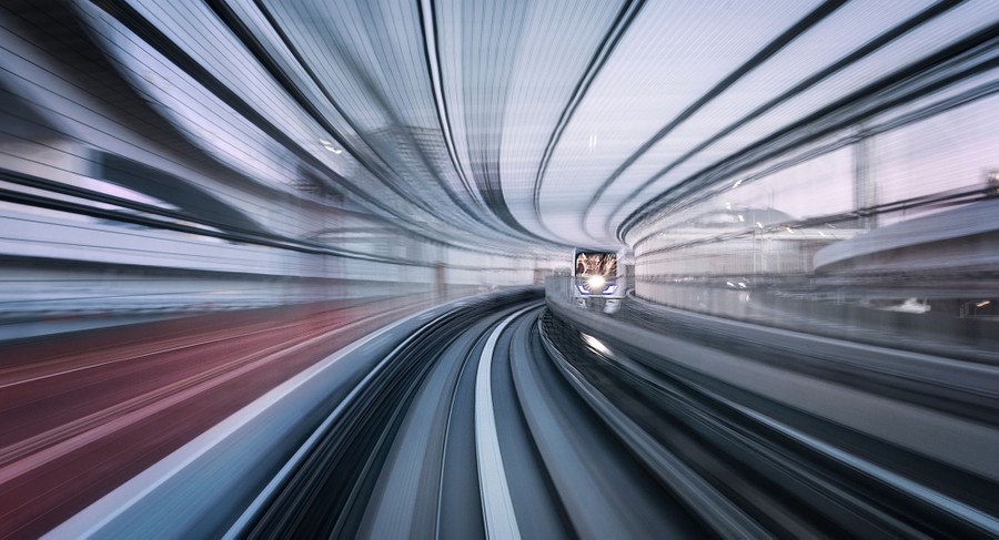 A blurred long-exposure photo of a train track and surrounding walls and fencing.