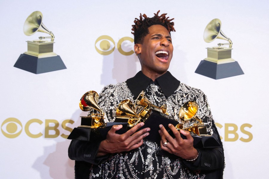 Performer Jon Batiste poses with an armful of Grammy Awards.