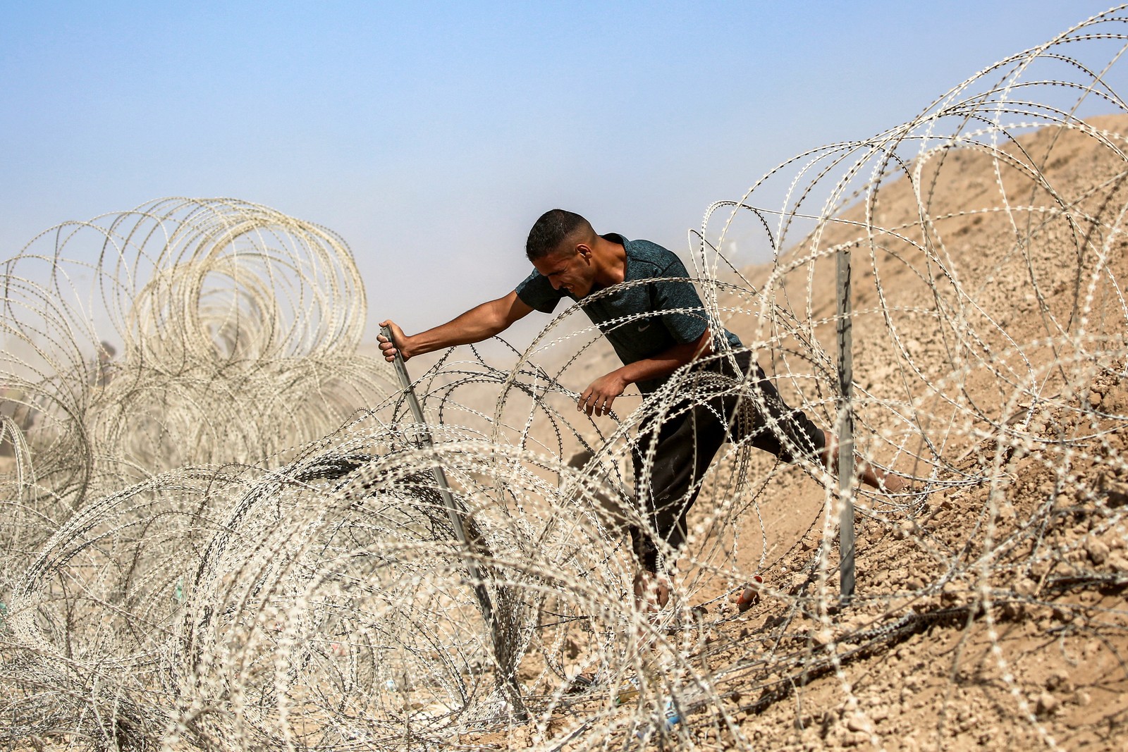A man attempts to remove parts of a razor-wire barrier.