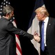 Falwell, left, smiles as he shakes hands with Trump, who appears to be mid-sentence.