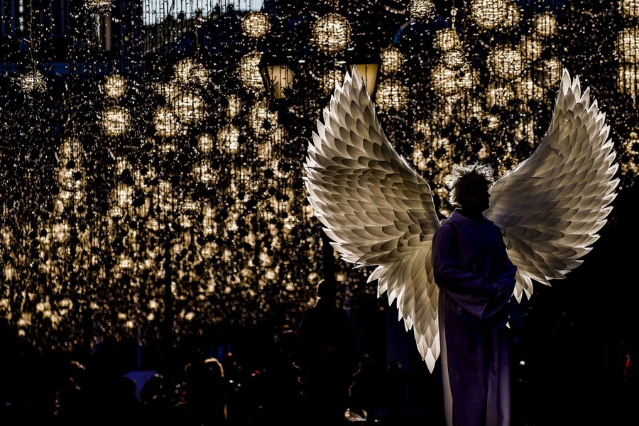 A person wears an angel costume under lights in a Moscow street.