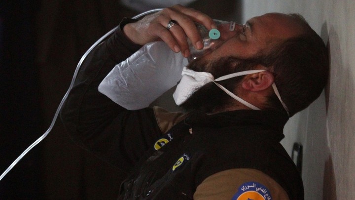 A civil defense member breathes through an oxygen mask, after what rescue workers described as a suspected gas attack in the town of Khan Sheikhoun.