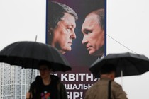 People walk past a campaign billboard, showing Poroshenko and Putin, in Kyiv.