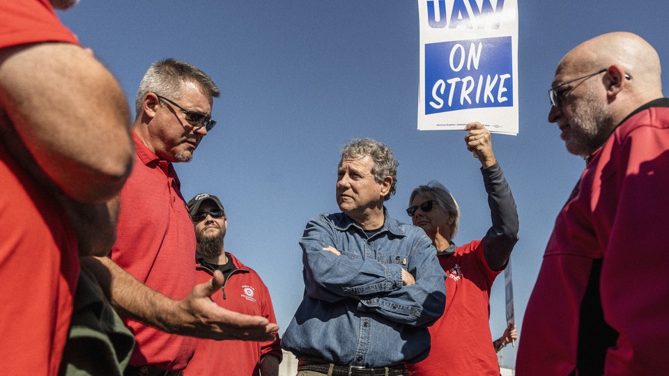 A color photograph of Sherrod Brown with UAW workers