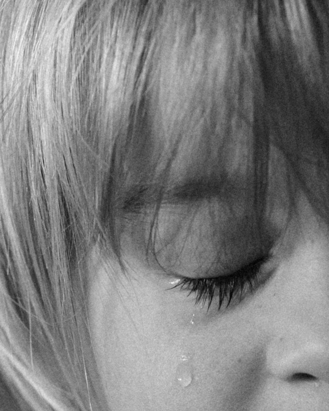 Cropped black-and-white close-up image of a child crying