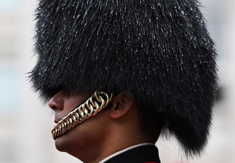 Raindrops hang from the fuzzy hat of a Royal guard.