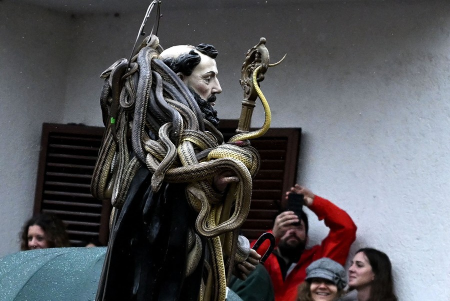 A life-size statue of a saint covered in live snakes