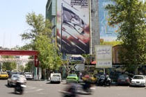 On a street in Tehran, anti-Israel banners cover the side of a high rise building.