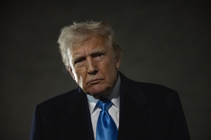 Donald Trump looks at the camera in front of a dark sky