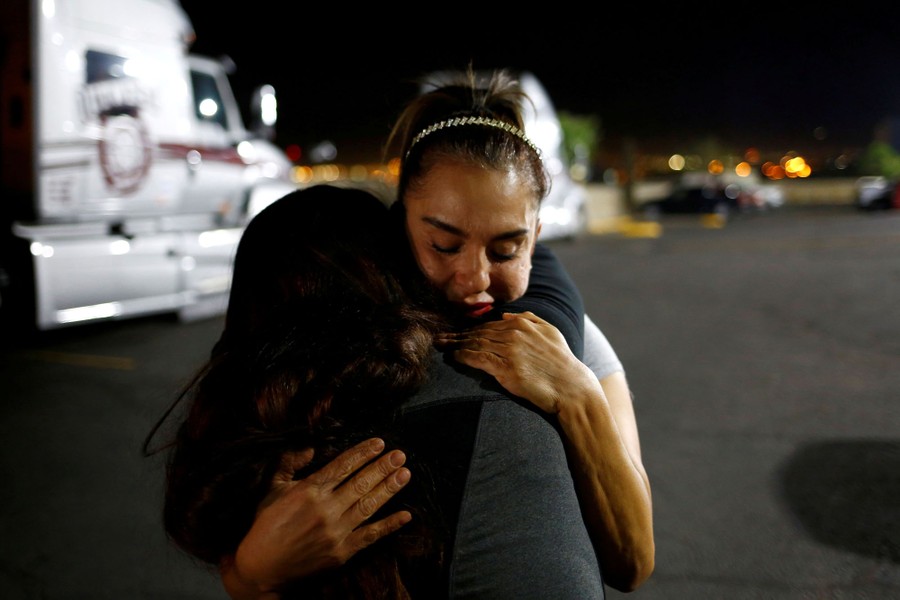 A mother and a daughter embrace in a parking lot.