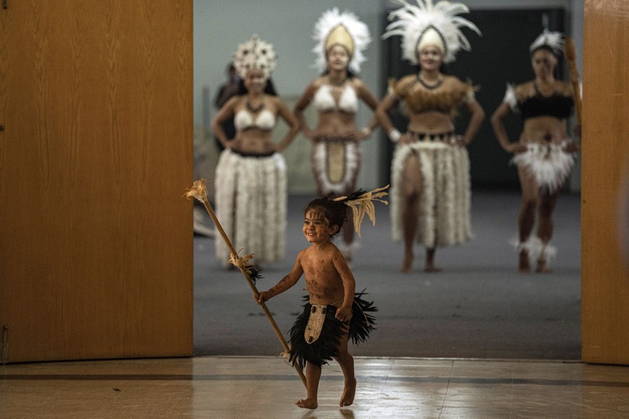 A child and several adults in traditional clothing wait to take part in a ceremony.