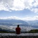 A man sits on a wall and enjoys the view.