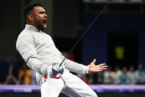 A fencer reacts after a match, arms outstretched, and mouth open.