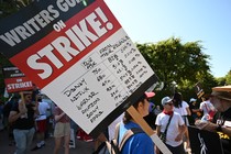 A writer's strike picket sign listing demands vs. streamer revenue