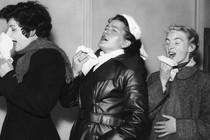 a row of people sneezing into handkerchiefs