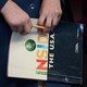 A student's hands hold a pencil in front of a book whose cover reads "Inside the USA"