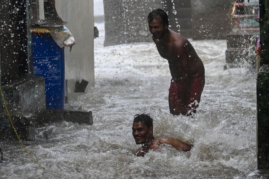 Two people play in water, splashing between buildings.