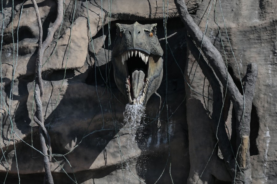 A dinosaur's head sticks out of the wall of a theme-park attraction